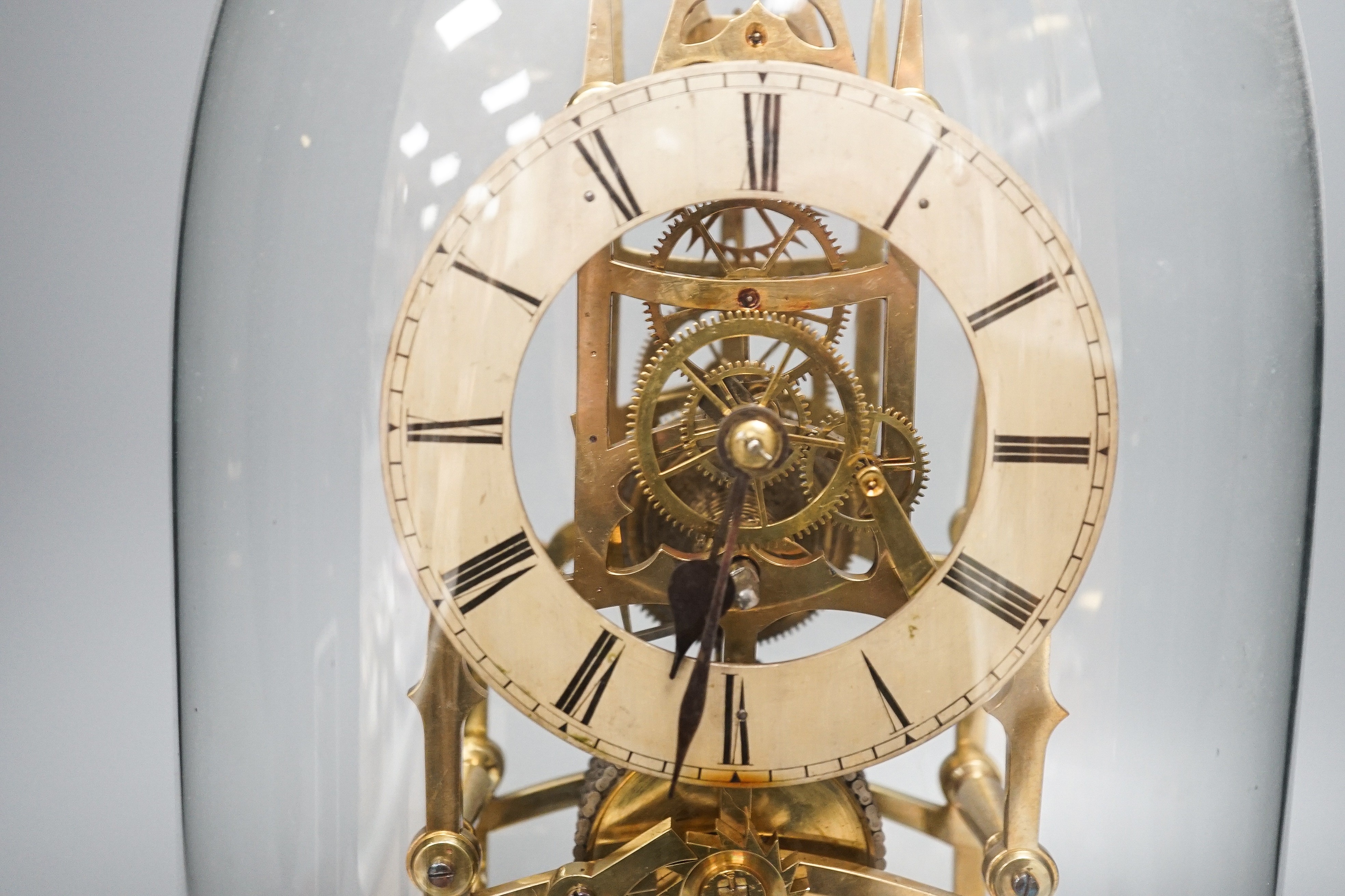 A Victorian brass skeleton clock, with single fusee movement, under a glass dome 43 cms high.